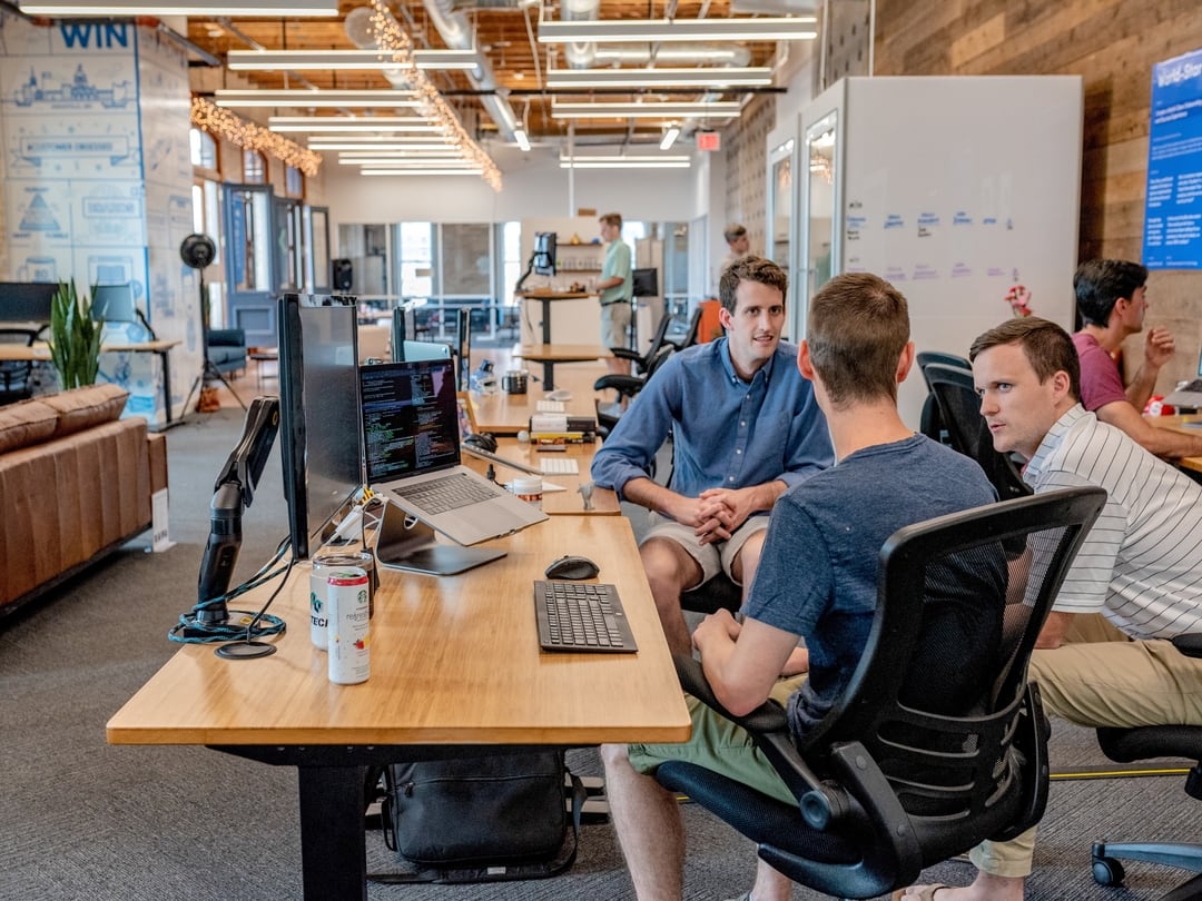 Team members talking at a desk in an open office during onboarding