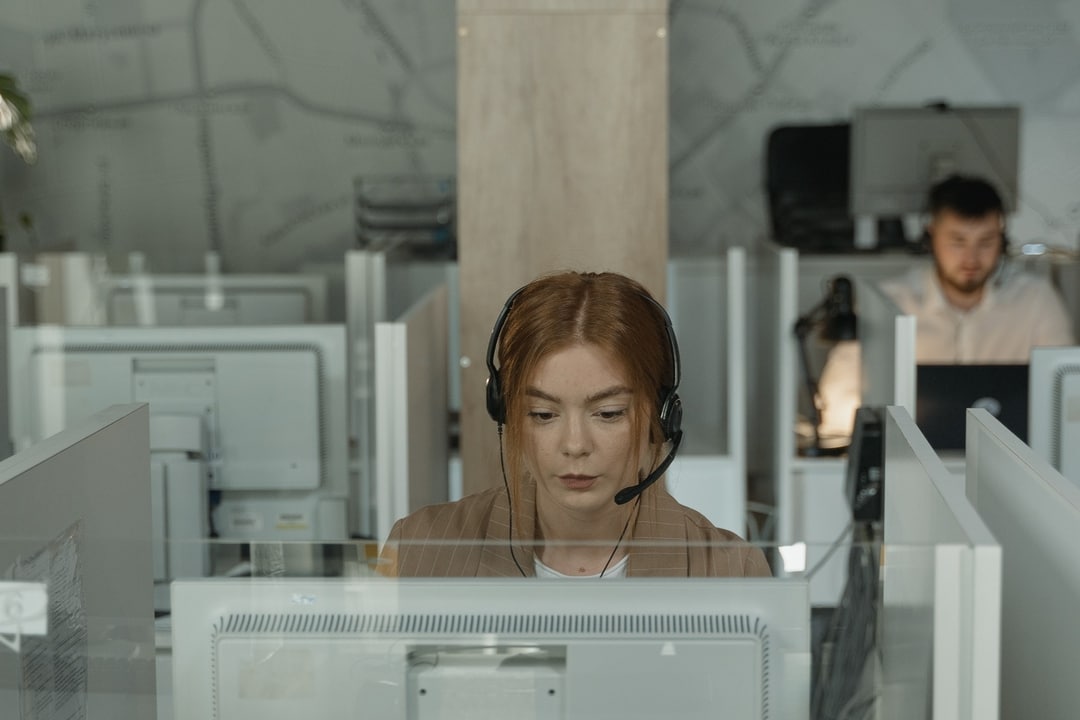 A customer support agent wearing a headset at a desk in a call center