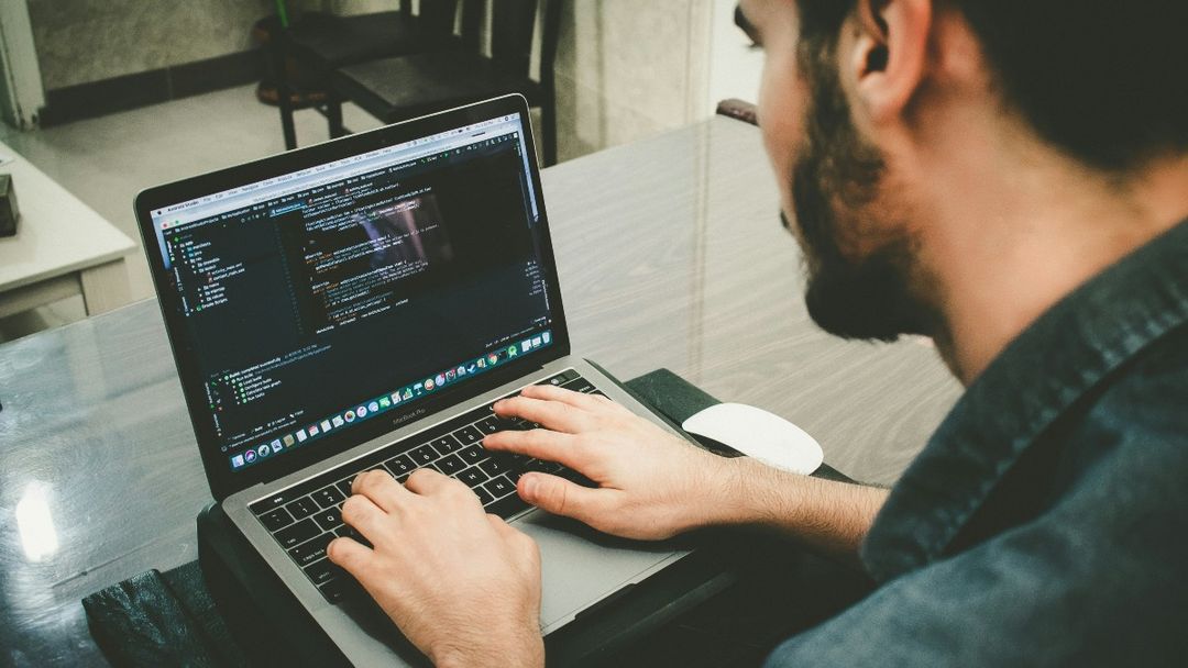 Developer writing code in a dark IDE on a laptop